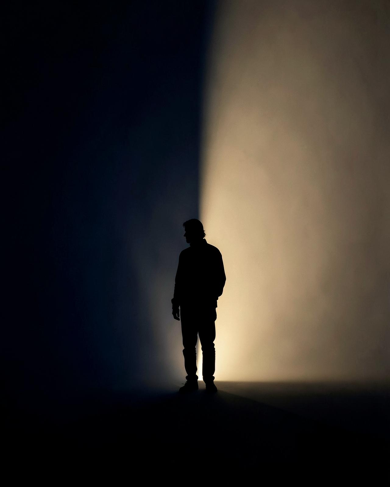 A person moving from deep shadow toward warm emerging light